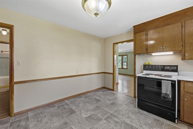 340 18th St NW, Cedar Rapids, IA 52405 - kitchen with range with electric cooktop, brown cabinetry, light countertops, and under cabinet range hood