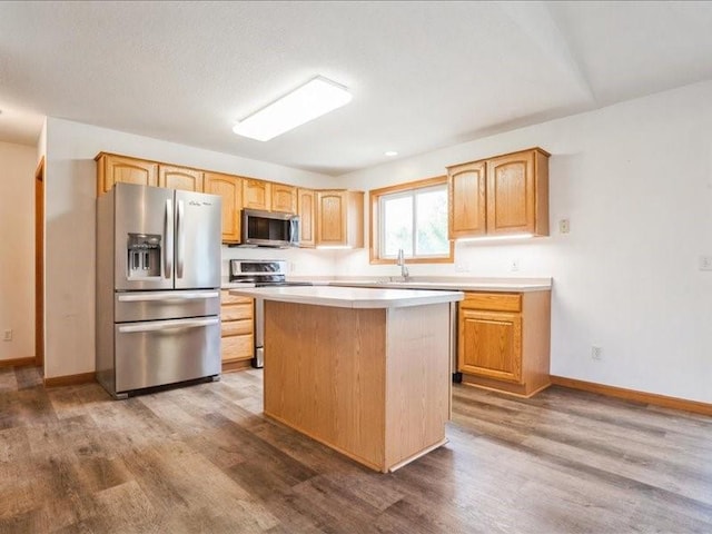 3182 62nd St, Shellsburg, IA 52332 - kitchen featuring appliances with stainless steel finishes, wood finished floors, a kitchen island, and light countertops