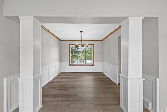 7603 Hampshire Dr NE, Cedar Rapids, IA 52402 - unfurnished dining area featuring wainscoting, a chandelier, a decorative wall, wood finished floors, and ornate columns