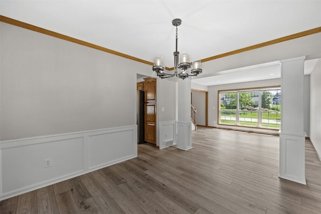 7603 Hampshire Dr NE, Cedar Rapids, IA 52402 - empty room with a chandelier, a wainscoted wall, wood finished floors, a decorative wall, and ornamental molding