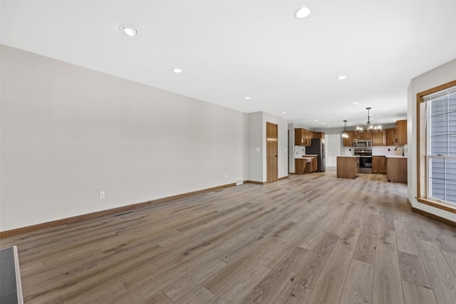 7603 Hampshire Dr NE, Cedar Rapids, IA 52402 - unfurnished living room with a chandelier, light wood finished floors, and recessed lighting