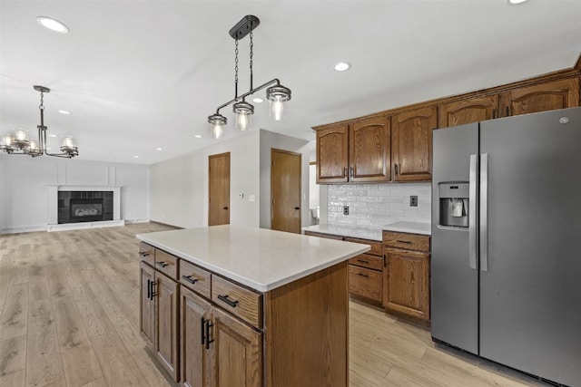 7603 Hampshire Dr NE, Cedar Rapids, IA 52402 - kitchen featuring stainless steel refrigerator with ice dispenser, light wood-style flooring, pendant lighting, backsplash, and light countertops