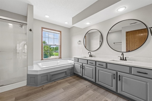 7603 Hampshire Dr NE, Cedar Rapids, IA 52402 - full bath with double vanity, a bath, wood finished floors, a shower, and recessed lighting