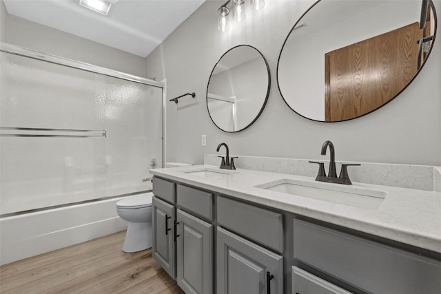 7603 Hampshire Dr NE, Cedar Rapids, IA 52402 - bathroom with double vanity, wood finished floors, and enclosed tub / shower combo