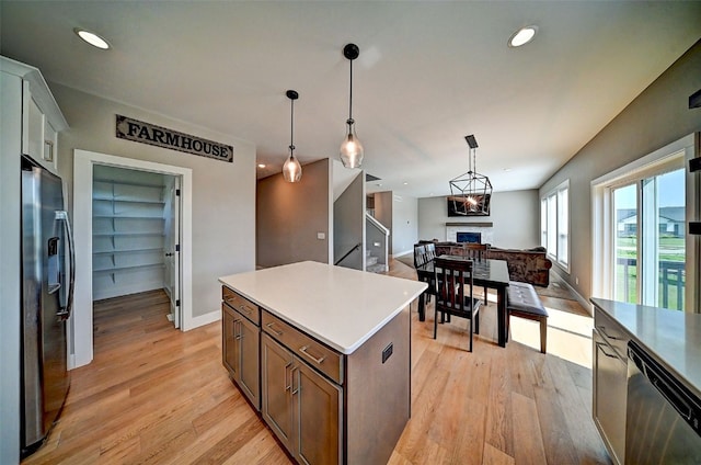 509 Grey Slate Dr SW, Cedar Rapids, IA 52404 - kitchen featuring stainless steel appliances, a fireplace, open floor plan, light wood finished floors, and decorative light fixtures