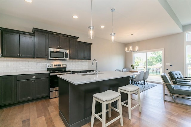 806 Crestview Dr, Solon, IA 52333 - kitchen with appliances with stainless steel finishes, a chandelier, tasteful backsplash, wood finished floors, and recessed lighting