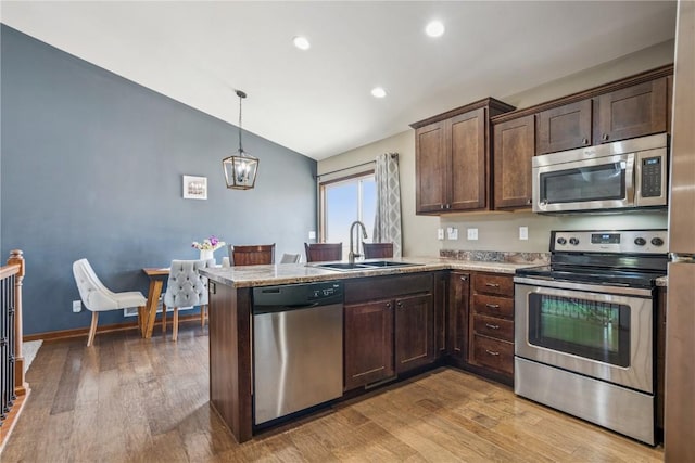 1301 Scarlet Sage Dr SW, Cedar Rapids, IA 52404 - kitchen with stainless steel appliances, vaulted ceiling, dark brown cabinets, light wood-type flooring, and a peninsula