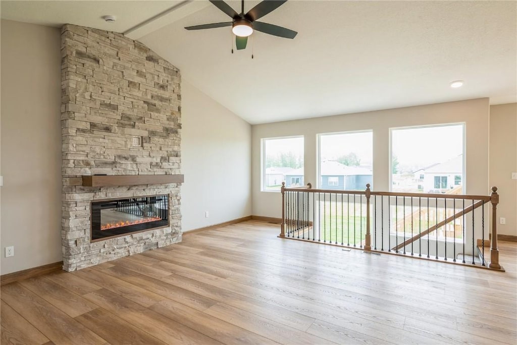 3339 Center Ct, Robins, IA 52328 - unfurnished living room featuring a stone fireplace, a ceiling fan, wood finished floors, and lofted ceiling