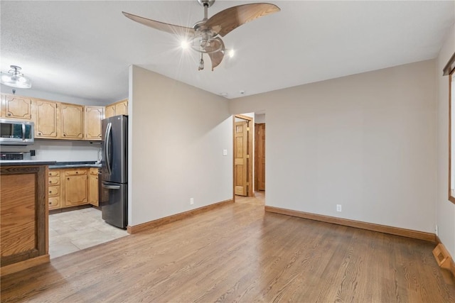 5315 E Ave NW, Cedar Rapids, IA 52405 - kitchen with stainless steel microwave, freestanding refrigerator, light wood-type flooring, and ceiling fan