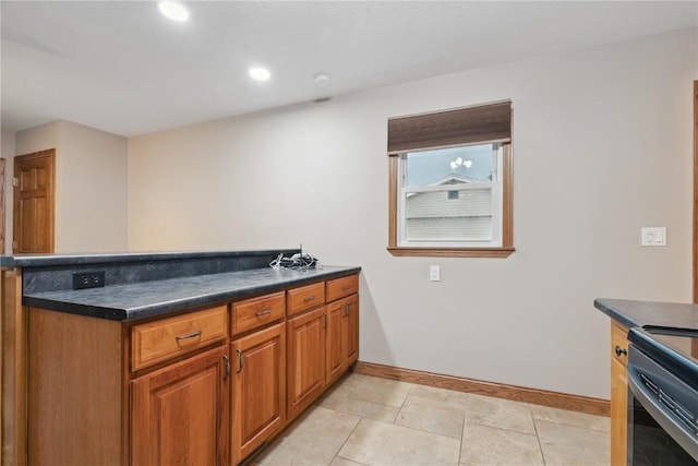 5315 E Ave NW, Cedar Rapids, IA 52405 - kitchen with brown cabinets, dark countertops, a peninsula, light tile patterned flooring, and recessed lighting