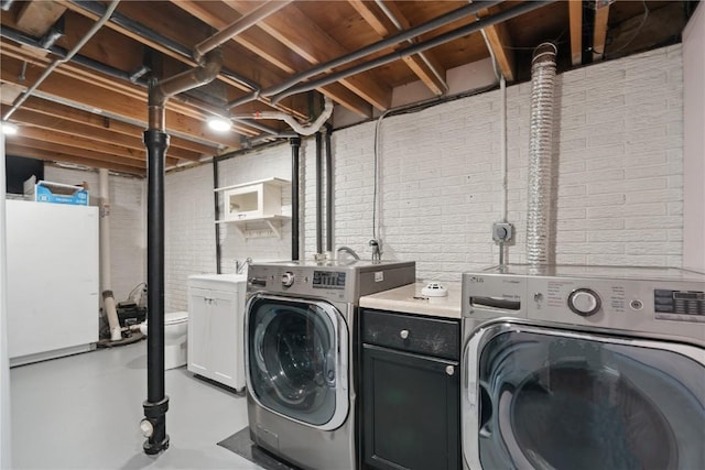 5315 E Ave NW, Cedar Rapids, IA 52405 - laundry area featuring separate washer and dryer, brick wall, and cabinet space