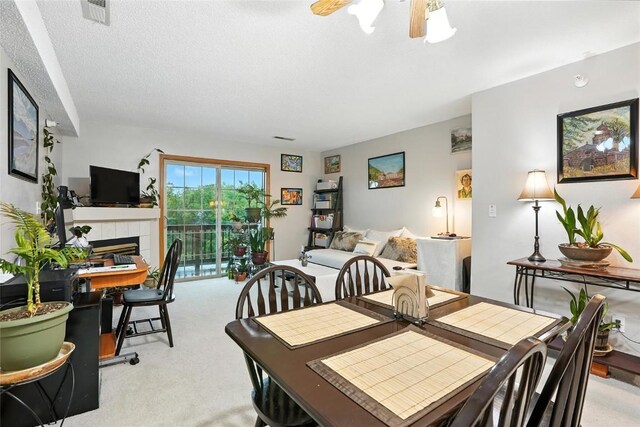 414 W Side Dr, Iowa City, IA 52246 - dining area featuring carpet floors, a tiled fireplace, and a ceiling fan