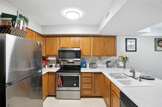 414 W Side Dr, Iowa City, IA 52246 - kitchen with stainless steel appliances, a textured ceiling, brown cabinetry, and light countertops