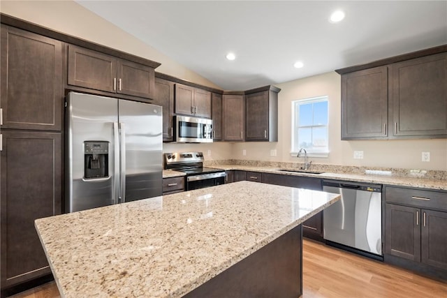 3880 Quail Trail Dr, Marion, IA 52302 - kitchen with stainless steel appliances, dark brown cabinetry, vaulted ceiling, light stone counters, and light wood-type flooring