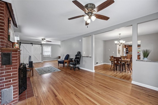 115 3rd St NE, Mount Vernon, IA 52314 - living room featuring a barn door, a ceiling fan, light wood-type flooring, and a chandelier