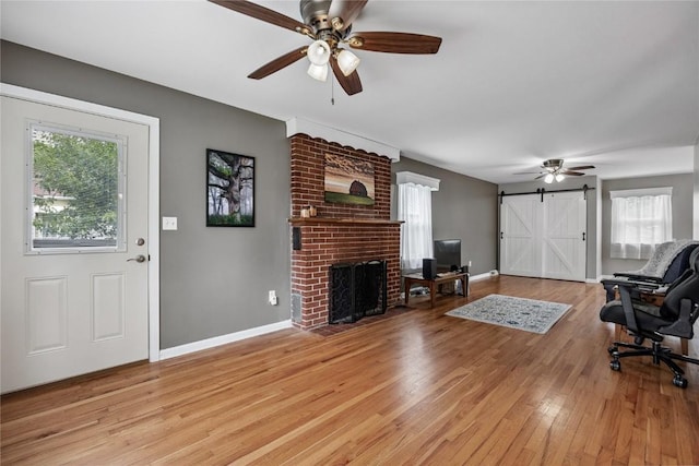 115 3rd St NE, Mount Vernon, IA 52314 - living room with a ceiling fan, light wood-type flooring, a brick fireplace, and a barn door