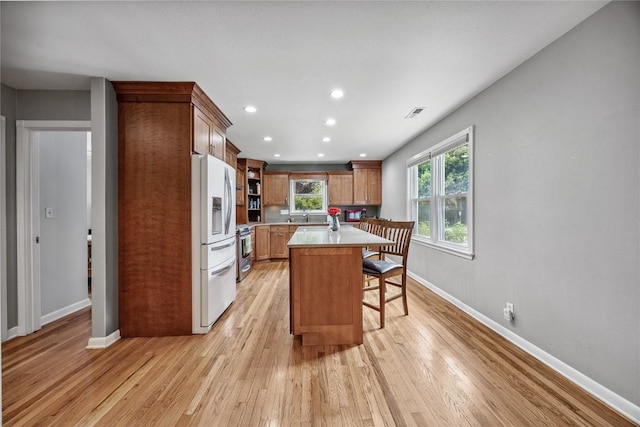 115 3rd St NE, Mount Vernon, IA 52314 - kitchen with white refrigerator with ice dispenser, light countertops, stainless steel range with electric cooktop, a breakfast bar area, and light wood finished floors