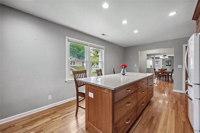 115 3rd St NE, Mount Vernon, IA 52314 - kitchen featuring freestanding refrigerator, recessed lighting, a kitchen island, light wood finished floors, and brown cabinetry