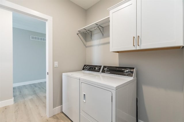 5750 Meadow Grass Cir SE, Cedar Rapids, IA 52403 - laundry area featuring separate washer and dryer, light wood-style floors, and cabinet space