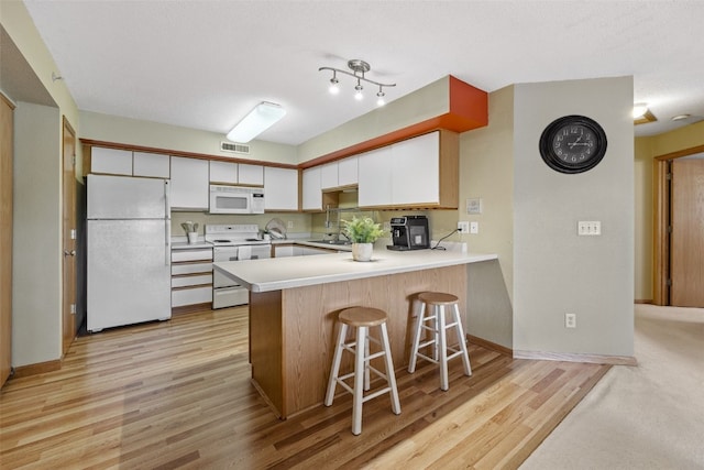 2861 Coral Ct Unit 302, Coralville, IA 52241 - kitchen with white appliances, a peninsula, white cabinets, light countertops, and light wood-style floors