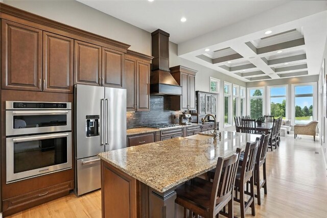 701 Sherwood Dr, Iowa City, IA 52245 - kitchen with stainless steel appliances, custom exhaust hood, light wood-type flooring, beamed ceiling, and light stone counters
