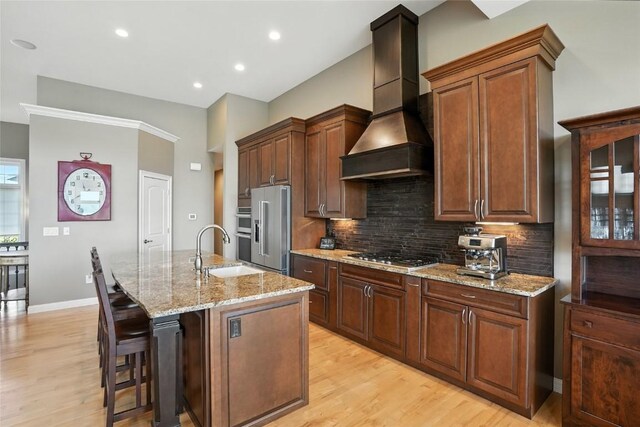 701 Sherwood Dr, Iowa City, IA 52245 - kitchen with custom exhaust hood, appliances with stainless steel finishes, light wood-style flooring, an island with sink, and recessed lighting