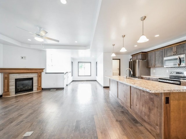 3502 Bluebird Dr SW, Cedar Rapids, IA 52404 - kitchen with stainless steel appliances, tasteful backsplash, a fireplace, a ceiling fan, and wood finished floors