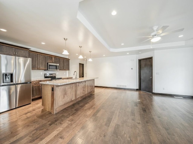 3502 Bluebird Dr SW, Cedar Rapids, IA 52404 - kitchen featuring appliances with stainless steel finishes, an island with sink, a ceiling fan, wood finished floors, and recessed lighting
