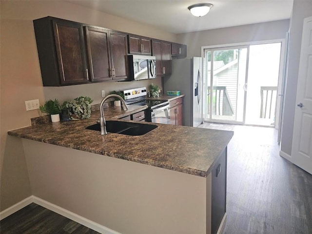 441 8th Ave SW, Cedar Rapids, IA 52404 - kitchen with appliances with stainless steel finishes, dark brown cabinetry, a peninsula, dark wood finished floors, and dark stone counters