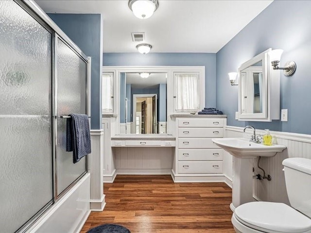 206 Kingbard Blvd, Waterloo, IA 50701 - bathroom featuring wood finished floors, wainscoting, and shower / bath combination with glass door