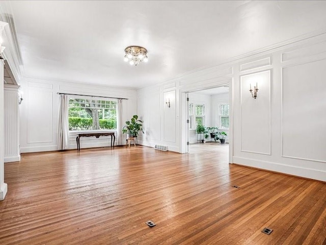 206 Kingbard Blvd, Waterloo, IA 50701 - unfurnished living room featuring a decorative wall, light wood-style floors, a chandelier, and ornamental molding