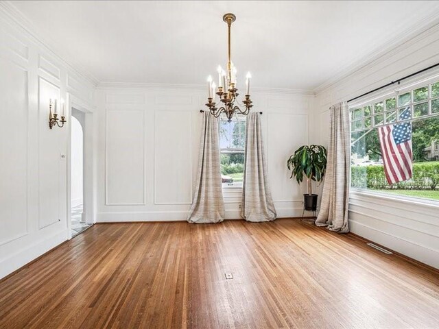 206 Kingbard Blvd, Waterloo, IA 50701 - unfurnished dining area with a decorative wall, a chandelier, wood finished floors, and ornamental molding