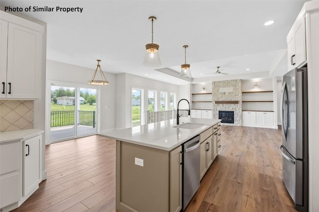 6706 Lauder Ln NE, Cedar Rapids, IA 52411 - kitchen with stainless steel appliances, open floor plan, a ceiling fan, light wood finished floors, and a fireplace