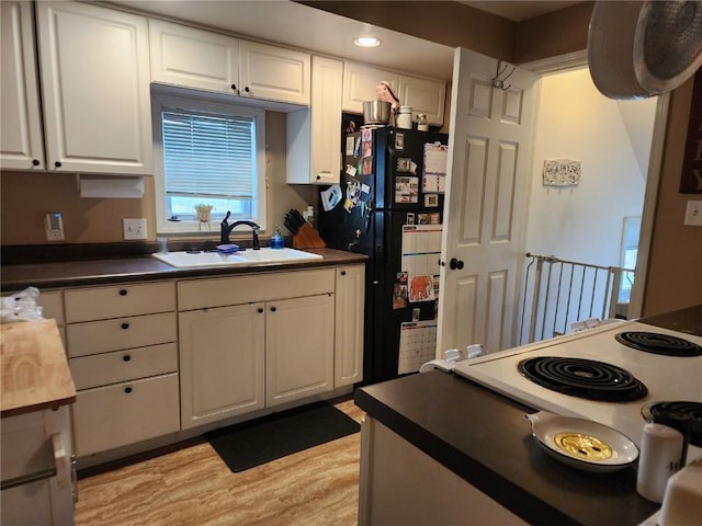 904 10th St, Belle Plaine, IA 52208 - kitchen featuring freestanding refrigerator, white cabinetry, light wood-style flooring, dark countertops, and recessed lighting