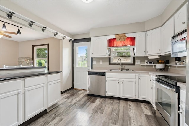 1708 Woodside Ct NW, Cedar Rapids, IA 52405 - kitchen featuring stainless steel appliances, white cabinets, light wood-style flooring, and healthy amount of natural light