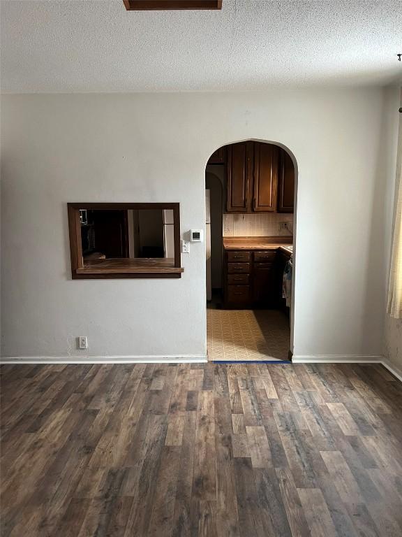201 S 8th Ave, Vinton, IA 52349 - unfurnished living room with arched walkways, wood finished floors, and a textured ceiling