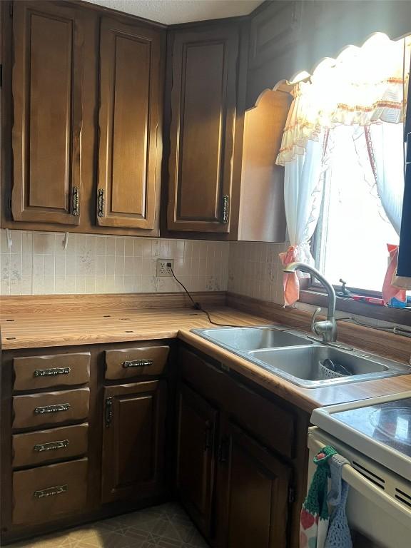 201 S 8th Ave, Vinton, IA 52349 - kitchen with backsplash, white range with electric cooktop, and dark brown cabinetry