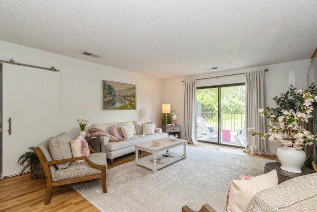 2135 1st Ave SE Unit 125, Cedar Rapids, IA 52402 - living area with a barn door, light wood-type flooring, and a textured ceiling