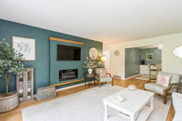 2135 1st Ave SE Unit 125, Cedar Rapids, IA 52402 - living area featuring wood finished floors, a textured ceiling, and a glass covered fireplace