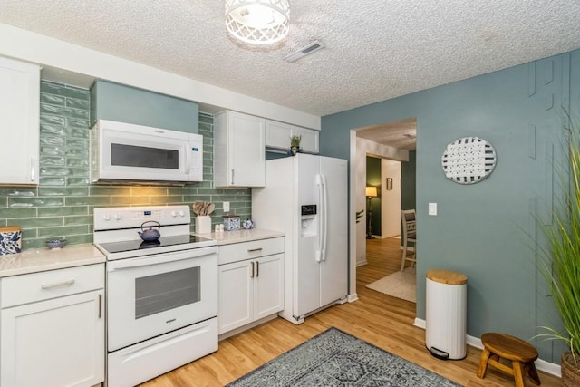 2135 1st Ave SE Unit 125, Cedar Rapids, IA 52402 - kitchen featuring white appliances, light countertops, light wood finished floors, tasteful backsplash, and a textured ceiling