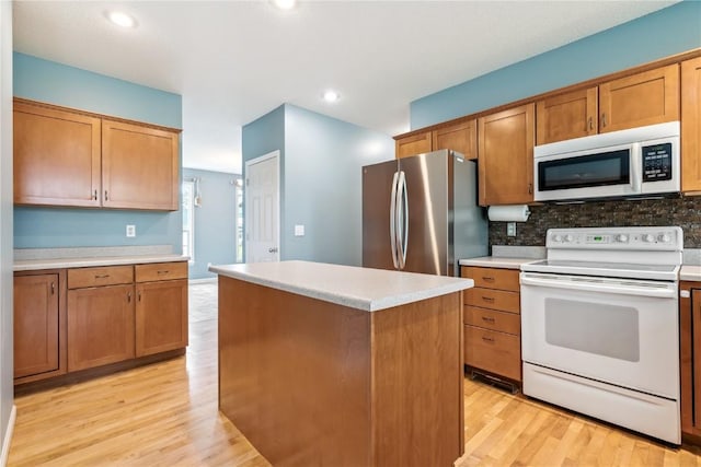 4309 Woodsonia Ct NW, Cedar Rapids, IA 52405 - kitchen featuring white appliances, light wood-type flooring, a center island, decorative backsplash, and recessed lighting