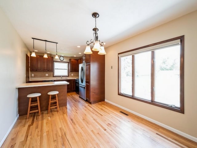 4634 Twin Pine Dr NE, Cedar Rapids, IA 52402 - kitchen with freestanding refrigerator, a peninsula, light wood finished floors, light countertops, and a kitchen breakfast bar