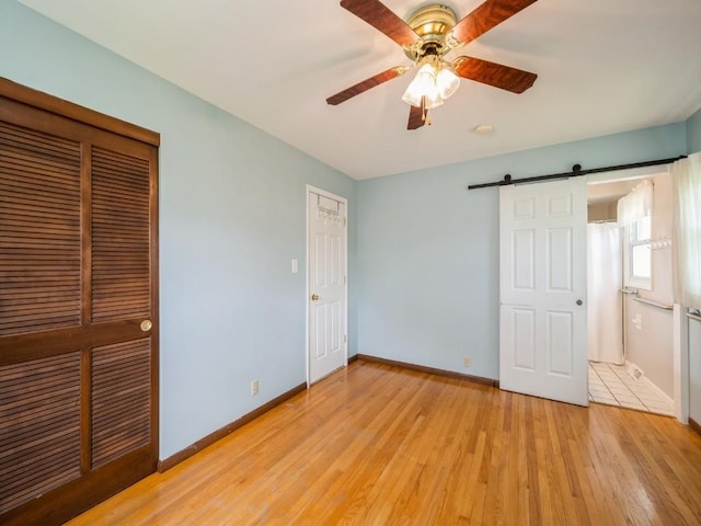 4634 Twin Pine Dr NE, Cedar Rapids, IA 52402 - unfurnished bedroom with light wood-type flooring, a barn door, and ceiling fan