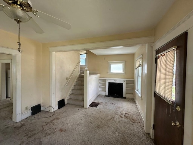 618 18th St SE, Cedar Rapids, IA 52403 - unfurnished living room featuring light colored carpet, stairway, a fireplace with flush hearth, and ceiling fan