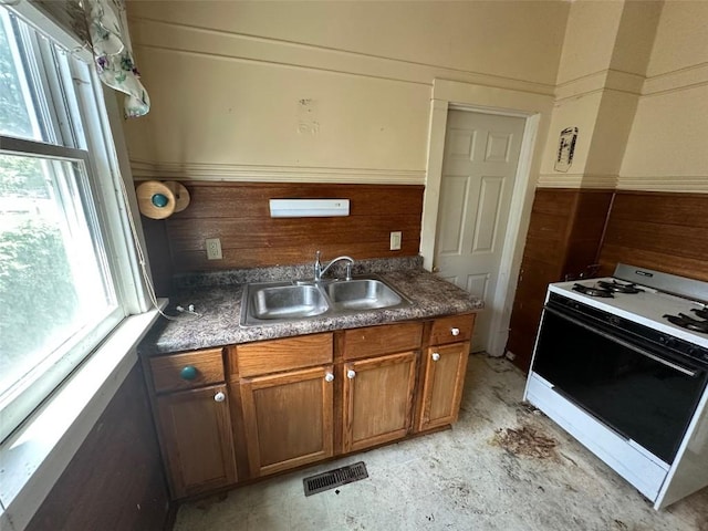 618 18th St SE, Cedar Rapids, IA 52403 - kitchen featuring white range with gas cooktop, healthy amount of natural light, and brown cabinetry