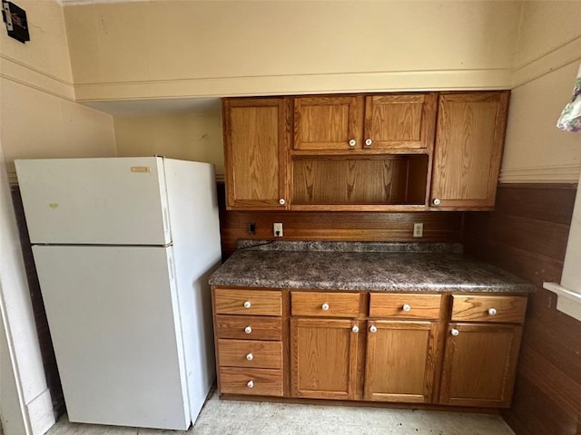 618 18th St SE, Cedar Rapids, IA 52403 - kitchen with freestanding refrigerator, brown cabinetry, and dark countertops