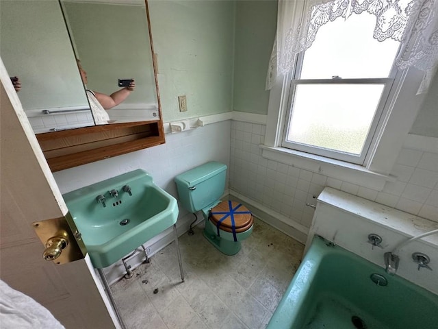 618 18th St SE, Cedar Rapids, IA 52403 - bathroom featuring tile walls, a wainscoted wall, and a bathtub