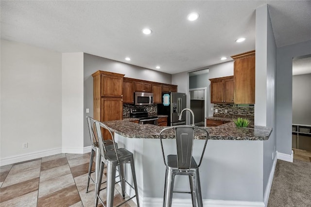 881 Shade Tree Ct, Lisbon, IA 52253 - kitchen with appliances with stainless steel finishes, decorative backsplash, a peninsula, recessed lighting, and a breakfast bar