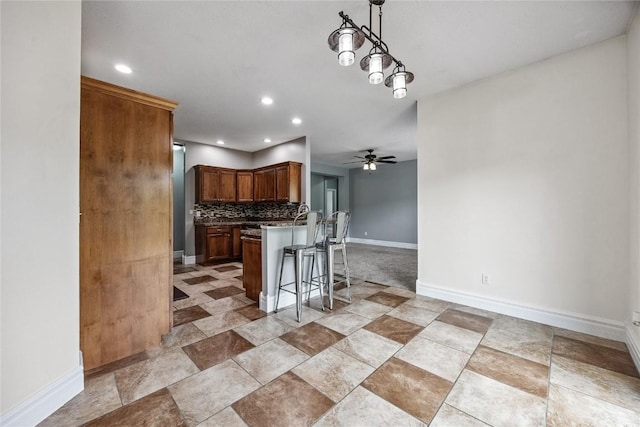 881 Shade Tree Ct, Lisbon, IA 52253 - kitchen featuring a kitchen bar, decorative backsplash, a ceiling fan, recessed lighting, and open floor plan