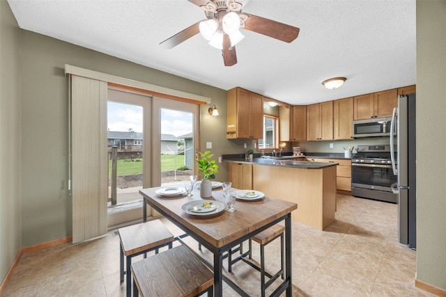 52 Thompson Dr, Palo, IA 52324 - kitchen with stainless steel appliances, a textured ceiling, dark countertops, a ceiling fan, and light tile patterned flooring